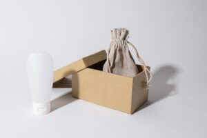 Minimalist photo of eco-friendly packaging with a cardboard box, pouch, and white plastic bottle.
